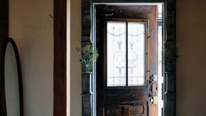 A wooden bench leading to a door with a frosted glass window, flanked by two potted plants.