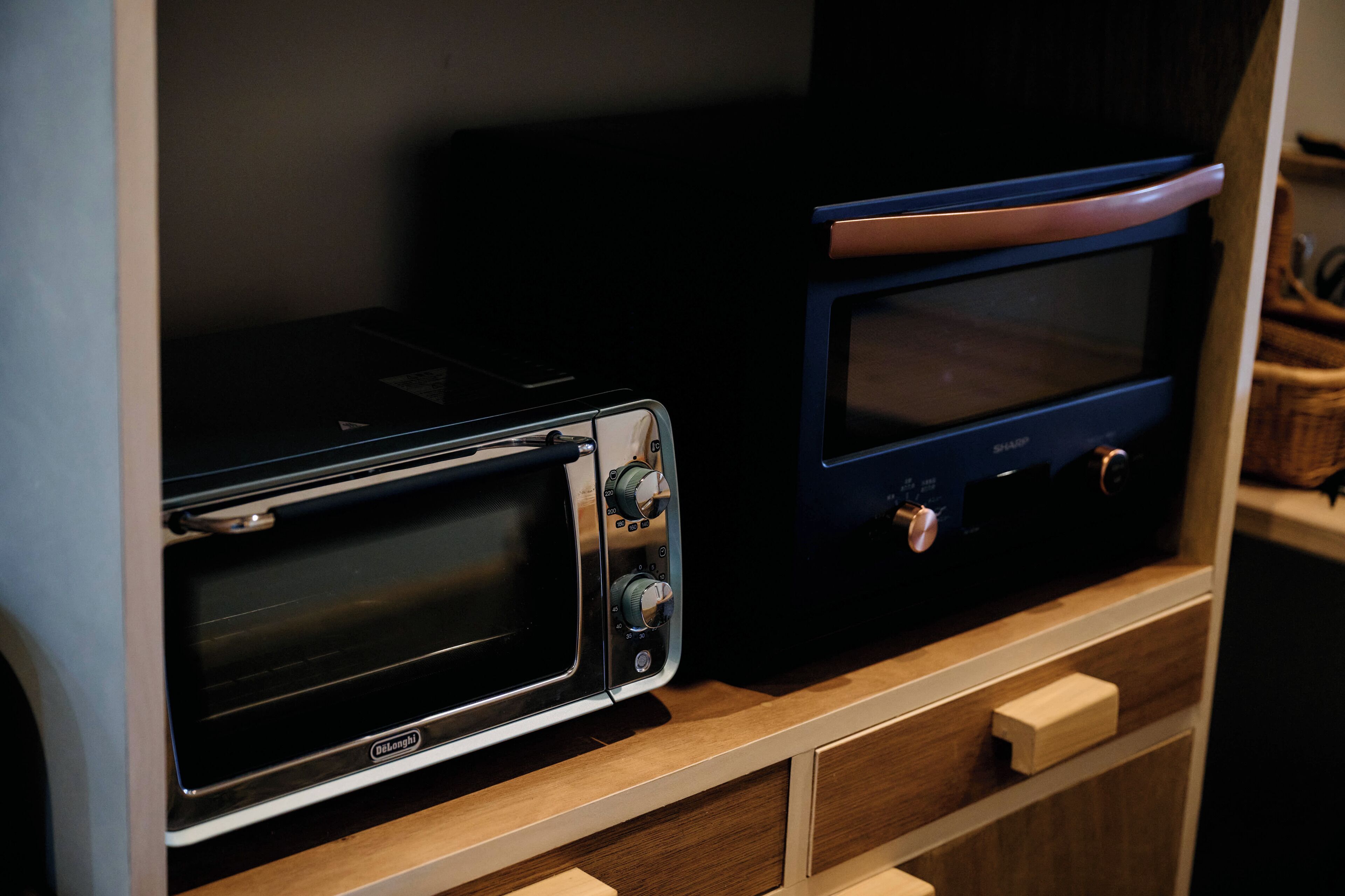 Una kitchenette con un horno tostador negro y un microondas azul.