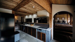 Una cocina moderna con una isla central, vigas de madera en el techo y vistas hacia un comedor.