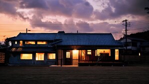 Una casa japonesa tradicional con techo de tejas, un porche de madera y un interior bien iluminado.