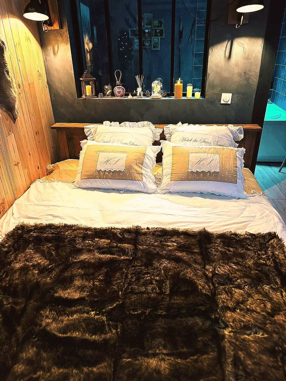A bedroom with a large bed, a wooden headboard, and a mirror above the bed.