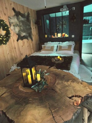 Un dormitorio acogedor con cama, mesita de noche y mesa de madera rústica con velas.