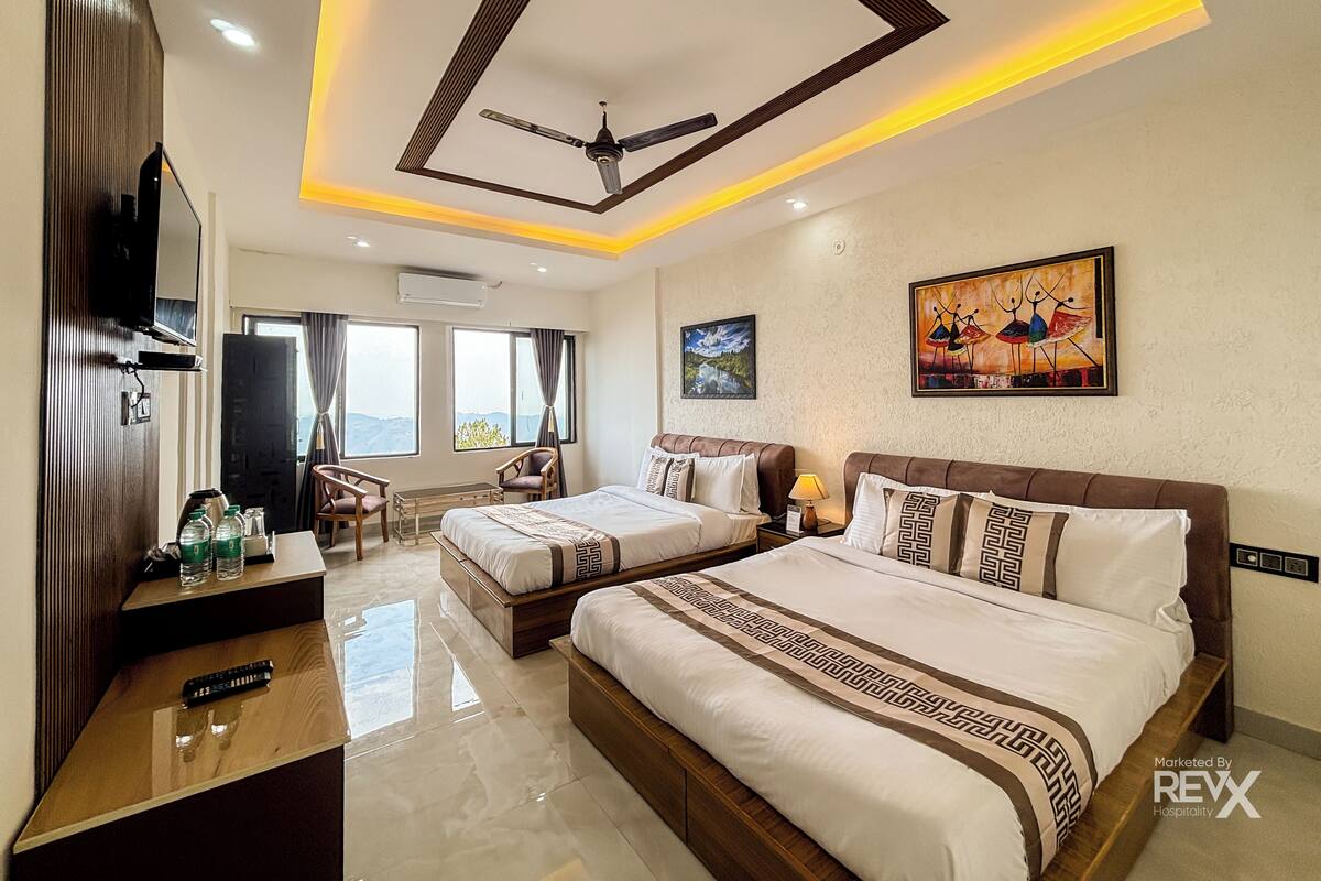 A hotel room with two beds, a TV, a ceiling fan, and artwork on the walls.
