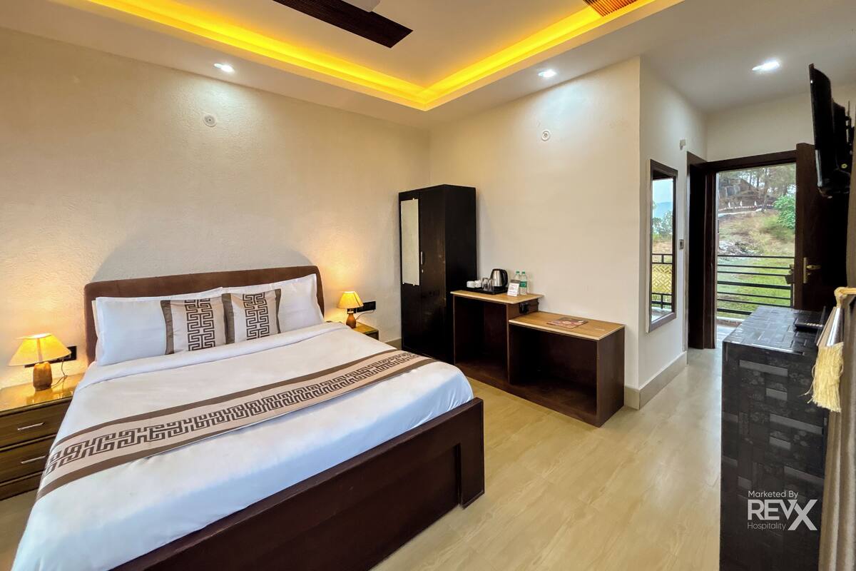 A modern hotel room with a large bed, bedside lamps, a ceiling fan, and a small desk with a mirror and a coffee maker.