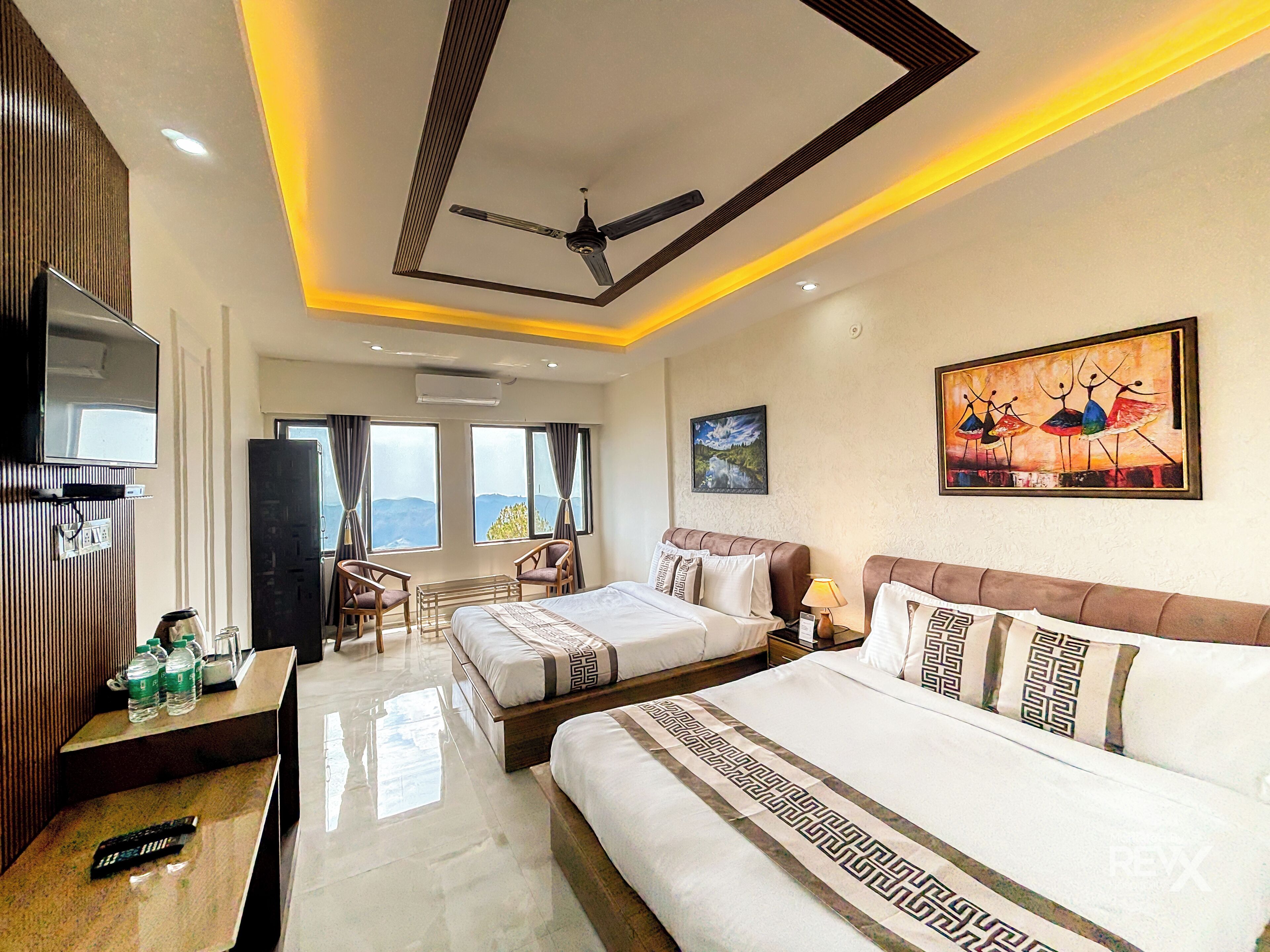 A hotel room with a bed, bedside table, lamp, and a TV mounted on the wall.