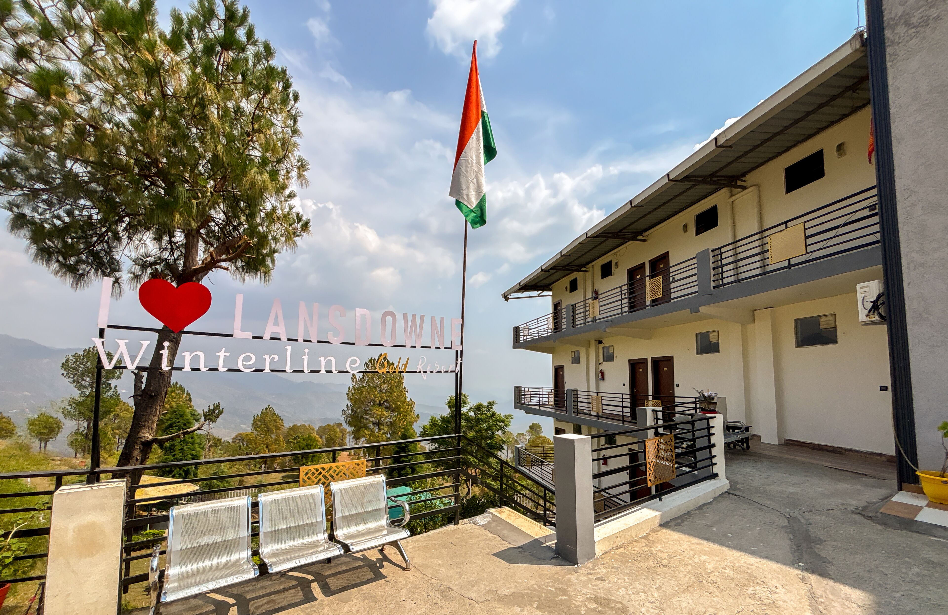 A building with a flagpole, a sign reading "LANSDOWN Winterline Resort," and a view of trees and mountains in the background.