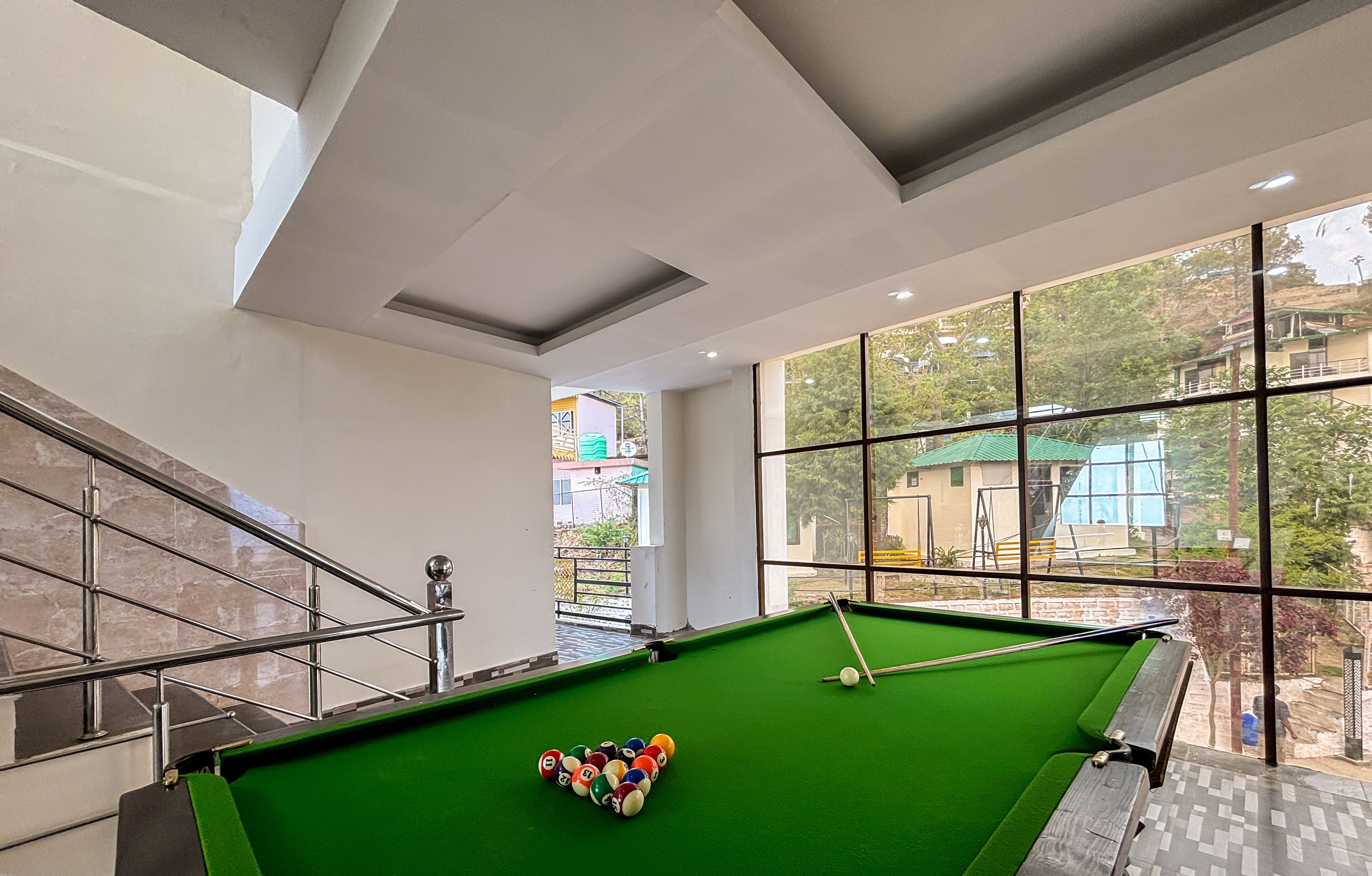 A pool table with balls and a window view.