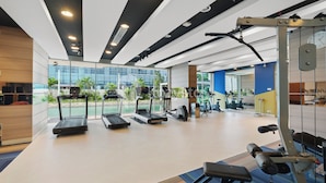 Een moderne sportschool met loopbanden, krachttoestellen en een groot raam met uitzicht op de omgeving.