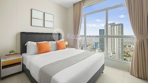 Een moderne hotelkamer met een groot bed, een nachtkastje en uitzicht op de stad door een groot raam.