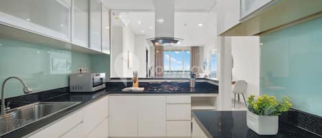 A modern kitchen with a black countertop, stainless steel sink, and a microwave.