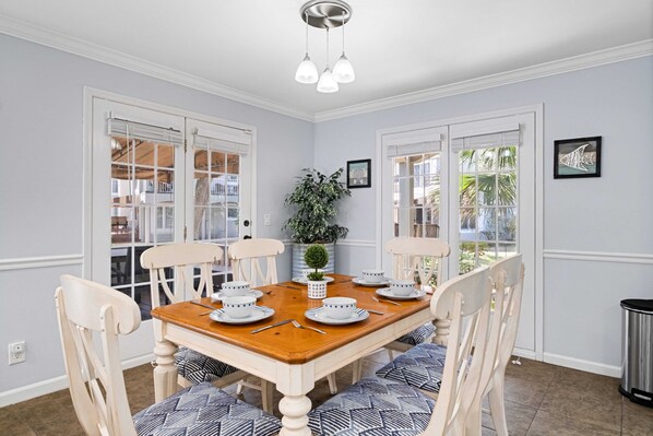 Un comedor con una mesa de madera dispuesta para seis personas, rodeada de seis sillas con cojines estampados.