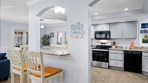 Una cocina moderna con armarios blancos, encimera de granito y electrodomésticos de acero inoxidable.