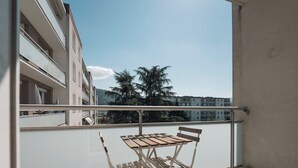 A balcony with a wooden table and chairs, overlooking a residential area with buildings and trees. - #HV | Le Panorama 🏔️ (Saint-Martin-d'Hères)