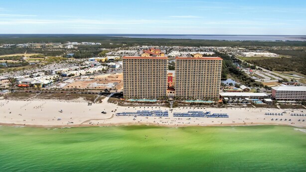 A coastal hotel with multiple high-rise buildings, a sandy beach, and a marina.