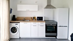 A compact kitchen with a washing machine, oven, microwave, and refrigerator. - Single-storey 3-bedroom house with garden in the heart of La Gacilly (La Gacilly)
