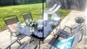 A patio area with a glass-top table, metal chairs, and a barbecue grill. - Single-storey 3-bedroom house with garden in the heart of La Gacilly (La Gacilly)