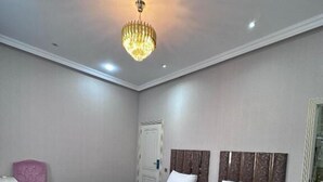 Una habitación de hotel con dos camas, un escritorio, una silla y un candelabro.