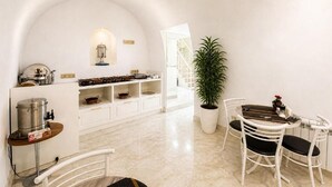 Un interior blanco con cocina, comedor y una planta en maceta.