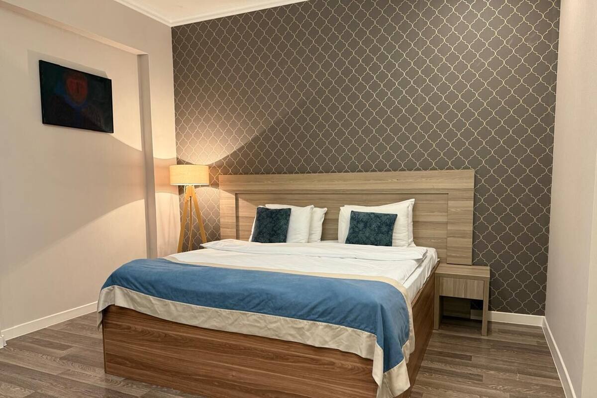 A neatly arranged bedroom with a wooden bed, a bedside table, and a lamp.