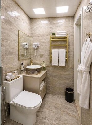 A bathroom with a toilet, sink, mirror, towel rack, and shower. - Central City Department Hotel (Baku)