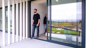 Ein moderner Gebäudeeingang mit Glastür und Blick auf eine grüne Landschaft.