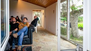 Ein modernes Interieur mit Steinboden, Holzboden und einer Glastür zu einem Außenbereich mit Baum und Grünpflanzen.