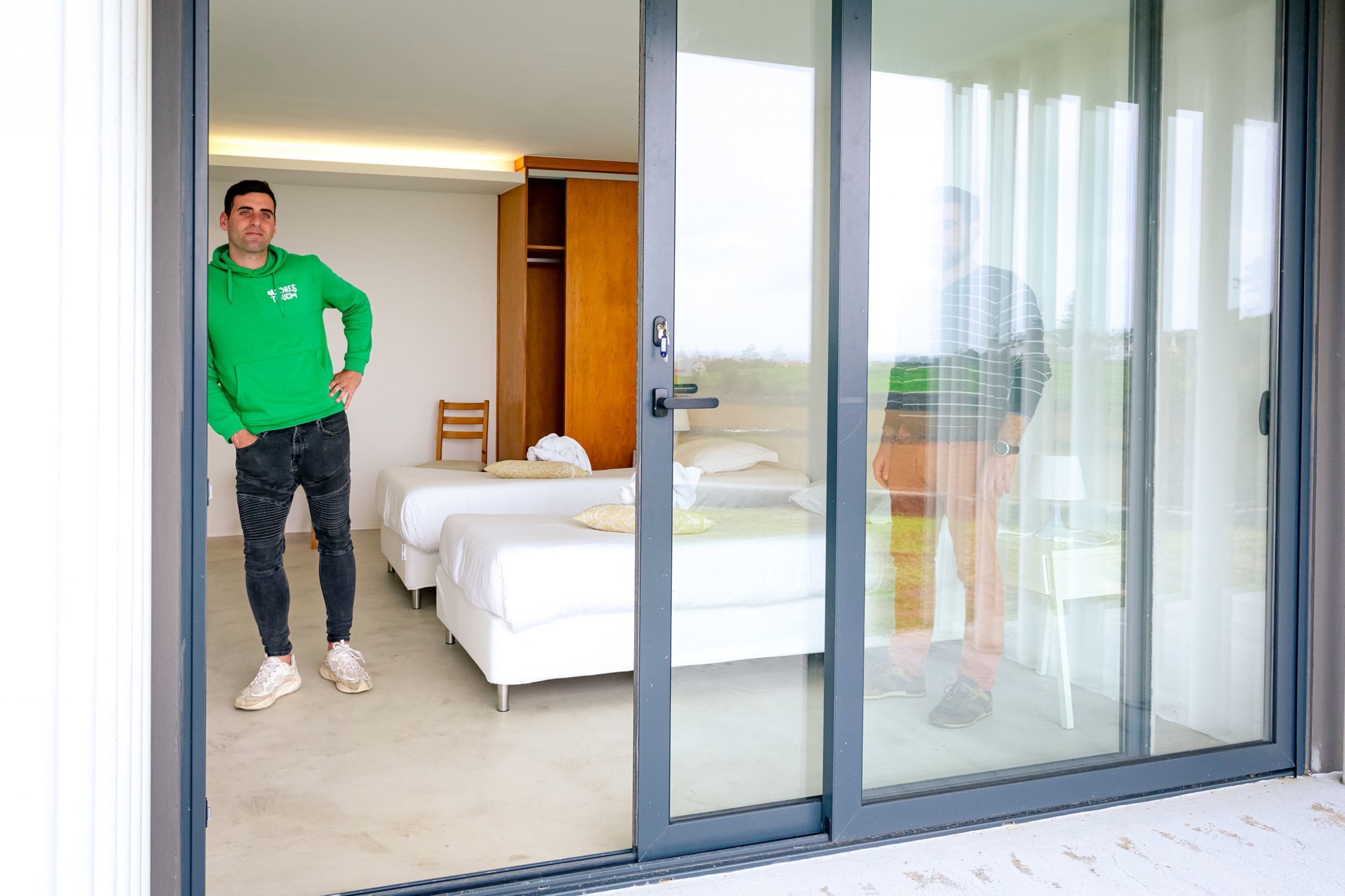 Ein Hotelzimmer mit einer großen Schiebeglasdoor, einem Bett, einem Holzschrank und einer kleinen Sitzecke.