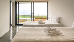 Ein Hotelzimmer mit zwei Betten, einem großen Fenster und Blick auf eine grüne Landschaft.