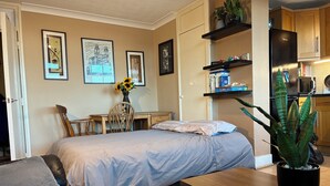 Ein Schlafzimmer mit Bett, Schreibtisch, Stuhl, Couchtisch und einer Zimmerpflanze.