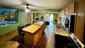 Una cocina con armarios de madera, encimera de granito y una estufa. Hay una zona de comedor con mesa y sillas.