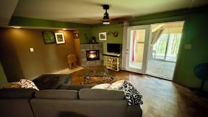 Una sala de estar con sofá, chimenea, televisor y puerta corrediza de vidrio que da a un espacio al aire libre.