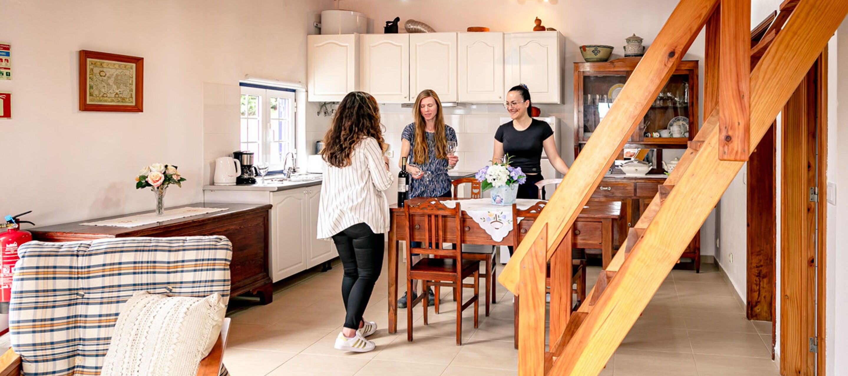 A modern kitchen with white cabinets, a dining table, and a staircase.