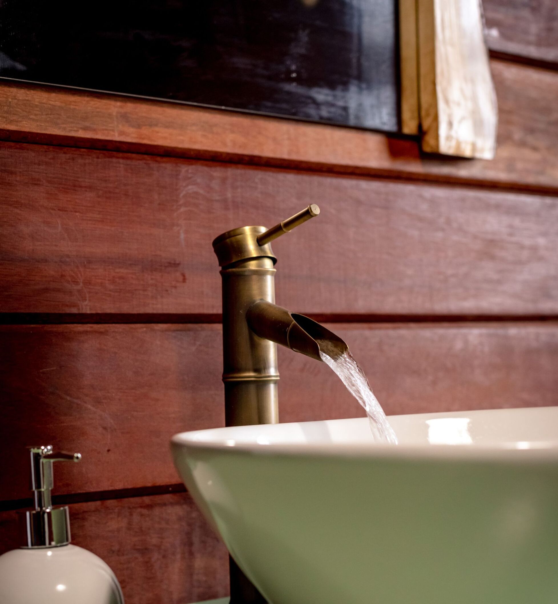Un baño con un grifo de bronce y un lavabo blanco.