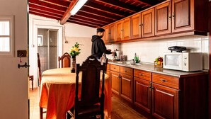A kitchen with wooden cabinets, a microwave, and a dining area with a table and chairs. - Moinho Pedra Pomes in Santa Cruz da Graciosa (Santa Cruz da Graciosa)
