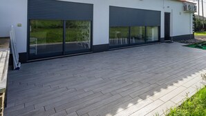 Un bâtiment moderne doté de deux grandes portes de garage, d’un toit plat et d’une terrasse dallée.