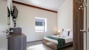 Une chambre à coucher avec un lit, une table de chevet, une fenêtre et une porte.