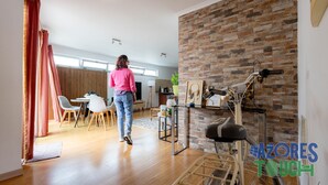 A spacious living room with a dining area, a brick accent wall, and a stationary exercise bike. - Olis House in Angra do Hero smo (Angra do Heroismo)