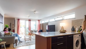 A modern kitchen with a central island, a washing machine, and a dining area with a table and chairs. - Olis House in Angra do Hero smo (Angra do Heroismo)
