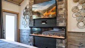 Una sala de estar moderna con chimenea, un televisor de pantalla plana montado en una pared de piedra y decoración mural.