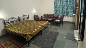 Un dormitorio con cama, una mesa, sillas, ventilador de techo, aire acondicionado y una ventana con cortinas.