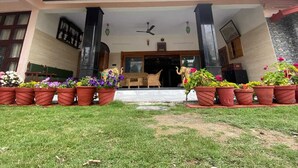 Un edificio con vestíbulo cubierto, plantas en macetas y un área de estar con mesa y sillas.