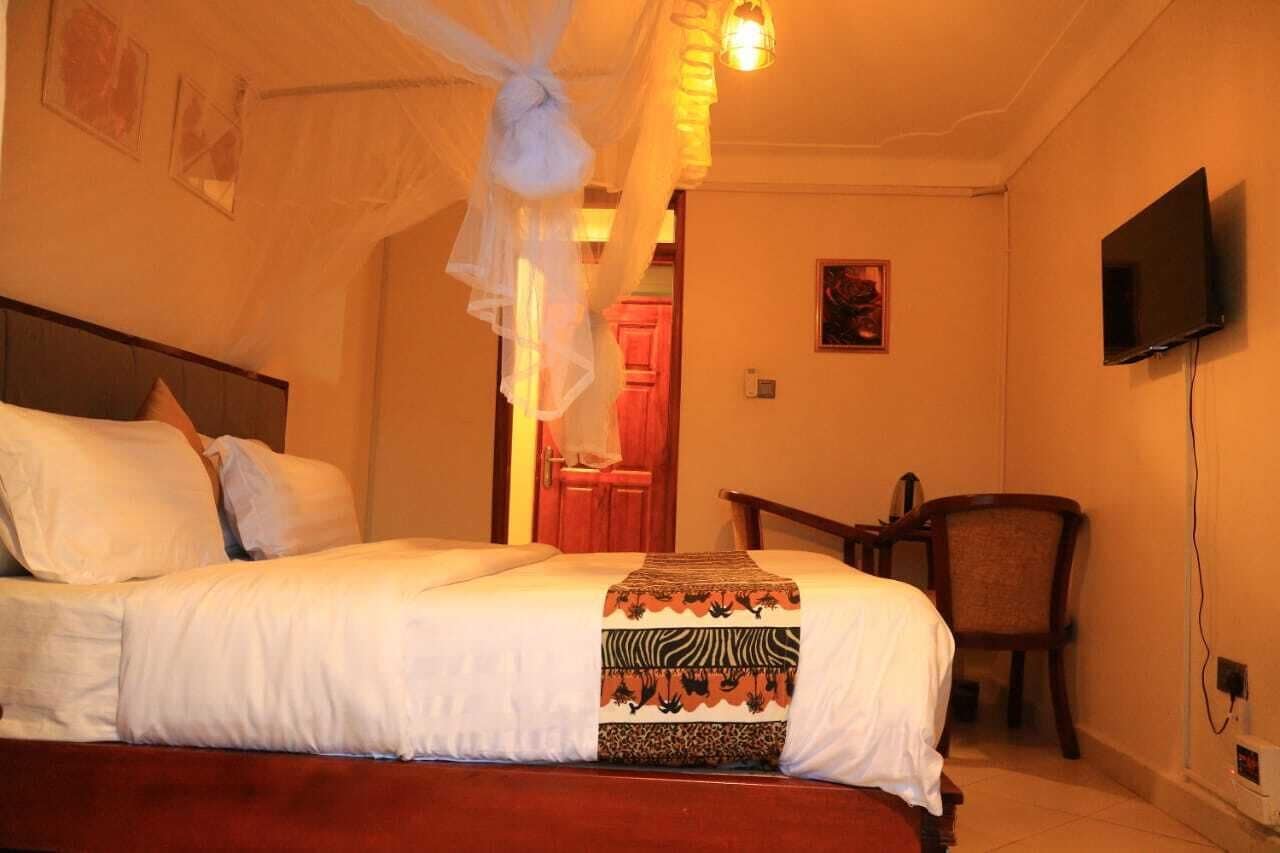 A bedroom with a bed, a chair, a television, and a door leading to another room.