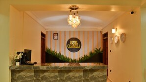 A hotel reception area with a marble counter, a chandelier, and a sign reading "HOTEL CASABELLA". - Hotel Casabella (Entebbe)