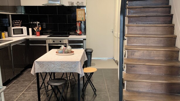A modern kitchen with a dining area, a staircase, and a view of the living area. - Gite La motte Forte, Arnay le Duc (Arnay-le-Duc)
