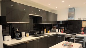 A modern kitchen with dark cabinetry, a white countertop, a microwave, a toaster, and a coffee machine. - Gite La motte Forte, Arnay le Duc (Arnay-le-Duc)
