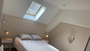 A bedroom with a skylight, a bed with patterned bedding, bedside lamps, and a dreamcatcher on the wall. - Gite La motte Forte, Arnay le Duc (Arnay-le-Duc)