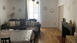 A dining area with a wooden table and chairs, a sofa with cushions, and a fireplace with decorative items. - Gite La motte Forte, Arnay le Duc (Arnay-le-Duc)