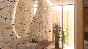 Un baño moderno con pared de piedra, tocador de madera y un espejo grande.