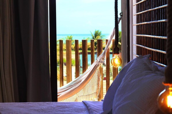 Una habitación con cama, una hamaca y vista al océano.