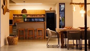 Una cocina moderna con armarios de madera, una barra y un comedor con mesa y sillas de madera.